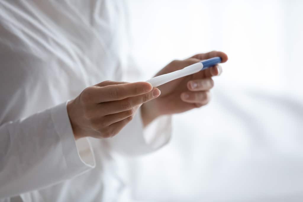 Close up of woman hold positive negative pregnancy ovulation test in hands in the morning expect baby, young pregnant female wait for results, fertility infertility treatment, maternity concept